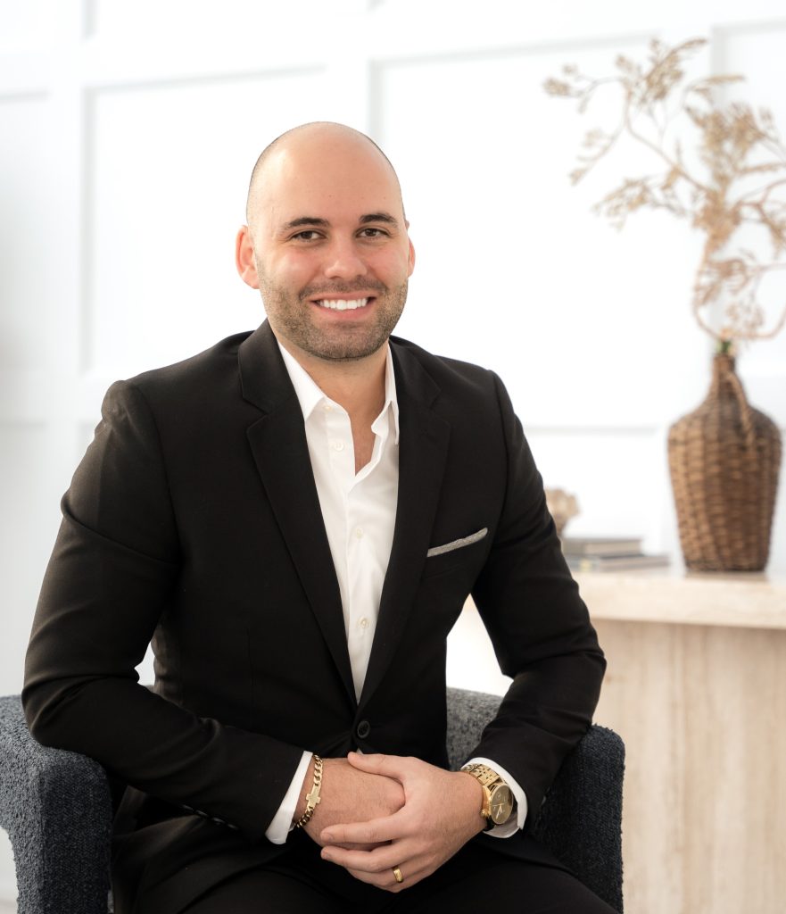 Confident Portuguese real estate agent Matthew Fernandes, dressed in a stylish black suit, poised for success in Ontario's property market.