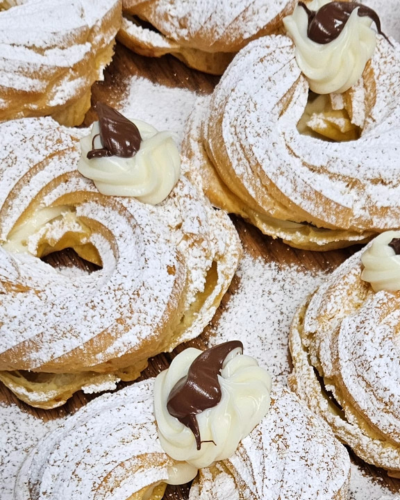 Elegant zeppole pastries adorned with whipped cream and chocolate at Brockton Village Bakery.