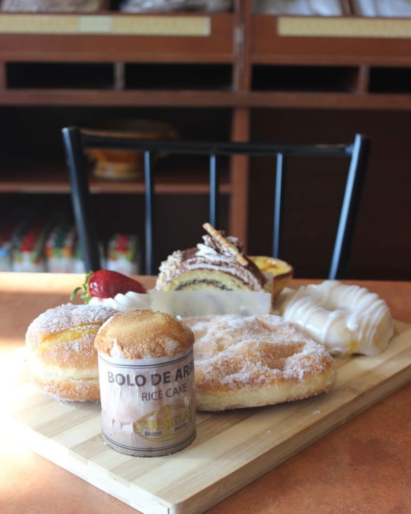 Array of Portuguese pastries on a wooden board at Nova Era Portuguese Bakery, Toronto.