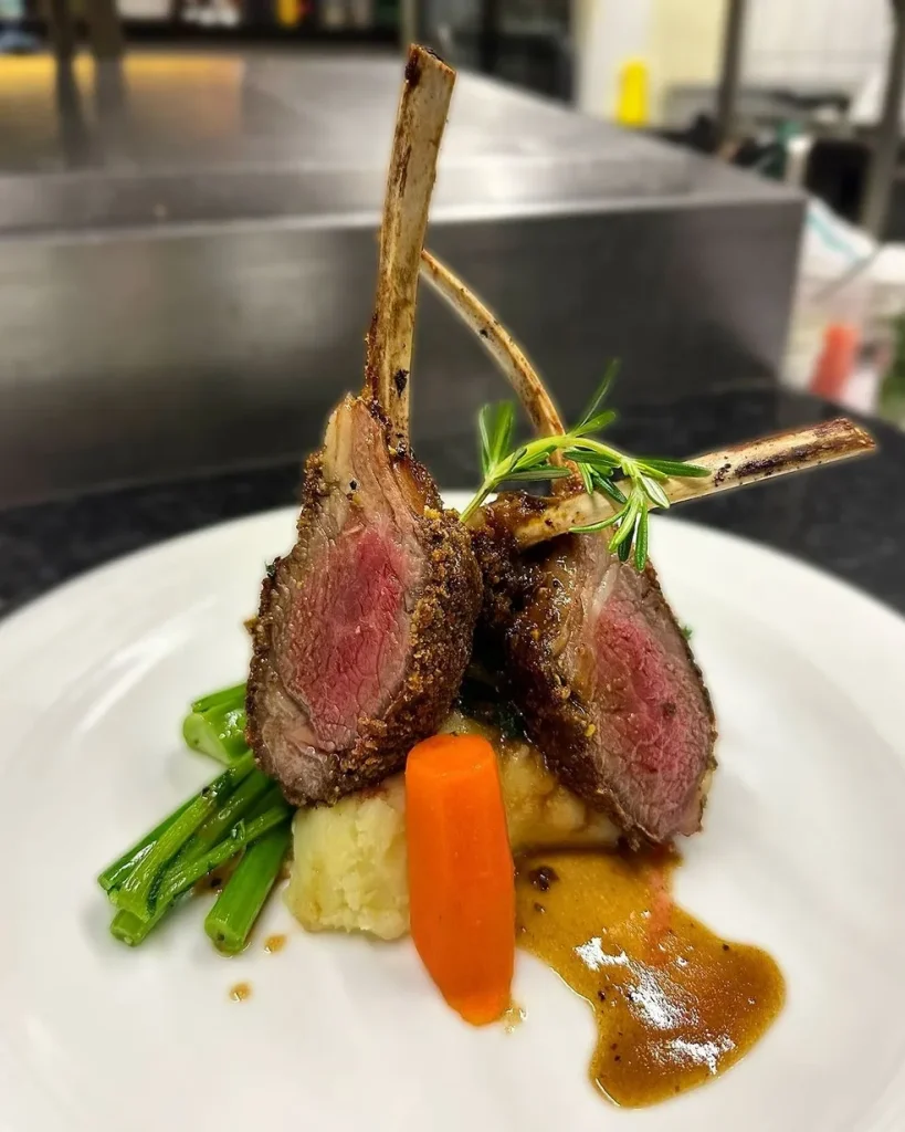 Juicy lamb chops presented on a white plate at Via Norte Restaurant.