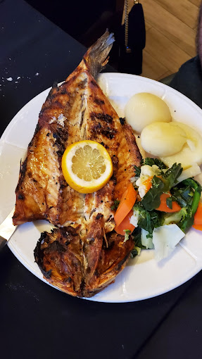 Grilled sea bass served with lemon, vegetables, and boiled potatoes, a Portuguese seafood specialty